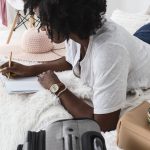 young Black woman laying on her bed doing copywriting exercises in her journal